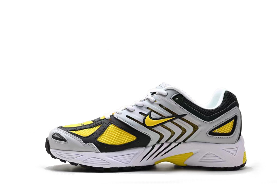 Side view of a white, gray, black, and yellow Nike sneaker with mesh panels and layered overlays