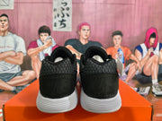 Rear view of a pair of black Nike sneakers showing textured heel panels and white ridged soles on an orange box.