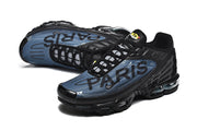 Pair of black and blue sneakers viewed at an angle, with Paris lettering across the side panels.