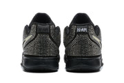 Rear view of the black Nike sneakers showing dense silver rhinestone-style decoration across the heels and black rubber midsoles.