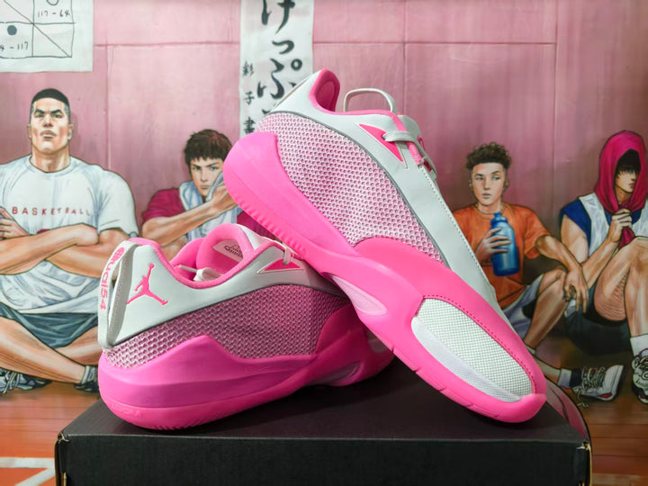 White and pink Jordan basketball sneakers shown at an angle on a black box.