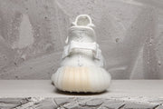 Rear view of a white Yeezy 350 V2 sneaker showing the heel pull tab and ribbed sole.
