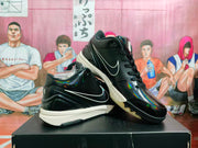 Angled view of a pair of black high-top basketball sneakers showing glossy panels, side branding and contrasting midsoles.