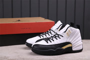 Pair of white, black, and gold Air Jordan 12 sneakers pictured with a Jordan shoe box