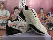 Side and angled views of cream, black, and pale pink Nike basketball shoes.