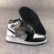 Side view showing the black outsole, white midsole, metallic silver panels, and attached metallic hangtag.