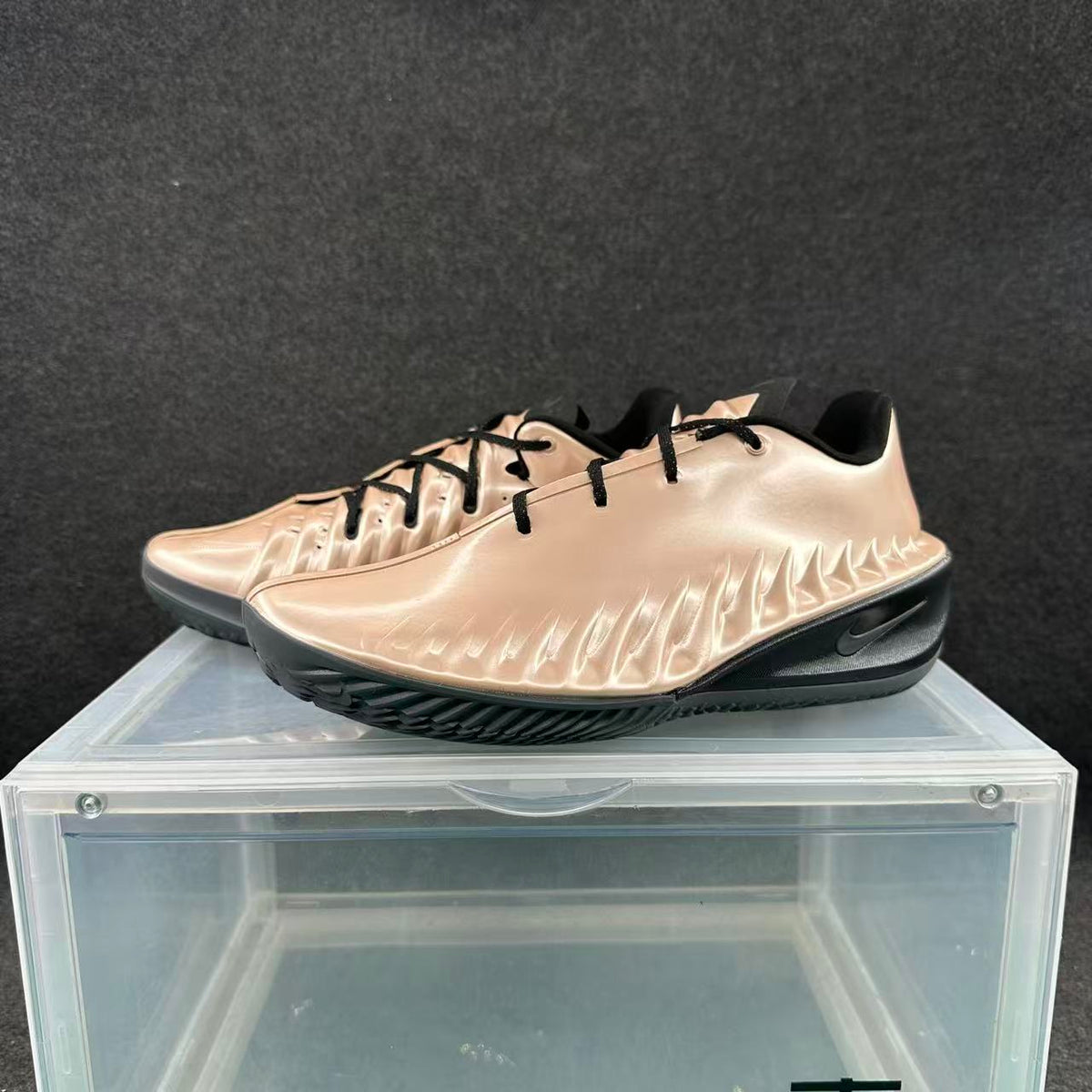Pair of metallic pink and black Nike basketball sneakers displayed on a clear stand.