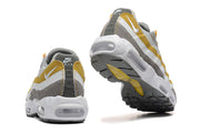 Heel and outsole views of grey, white and yellow Nike Air Max 95 TT sneakers.
