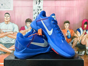 Blue Nike Kobe basketball shoes with white side Swoosh and red accent stitching.