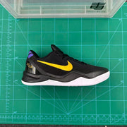 Side profile of the black and gold basketball sneaker photographed on a green measuring and cutting mat.