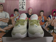 Front view of white and gray Nike basketball sneakers showing the textured toe panels, lemon-green laces, and padded tongues.
