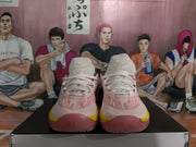 Front view showing the laces, peach pink upper, white toe area, and yellow outsole accents.