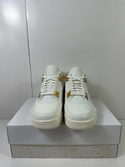 Front view of the white sneaker pair showing the laces, tongue branding, and gold-tone eyelet hardware.