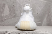 Rear view of a white sneaker showing the heel pull tab, textured upper, and ribbed translucent sole.