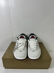 Front view of the pair showing white laces, red tongue branding, dragon-pattern detailing, and the decorative charm.
