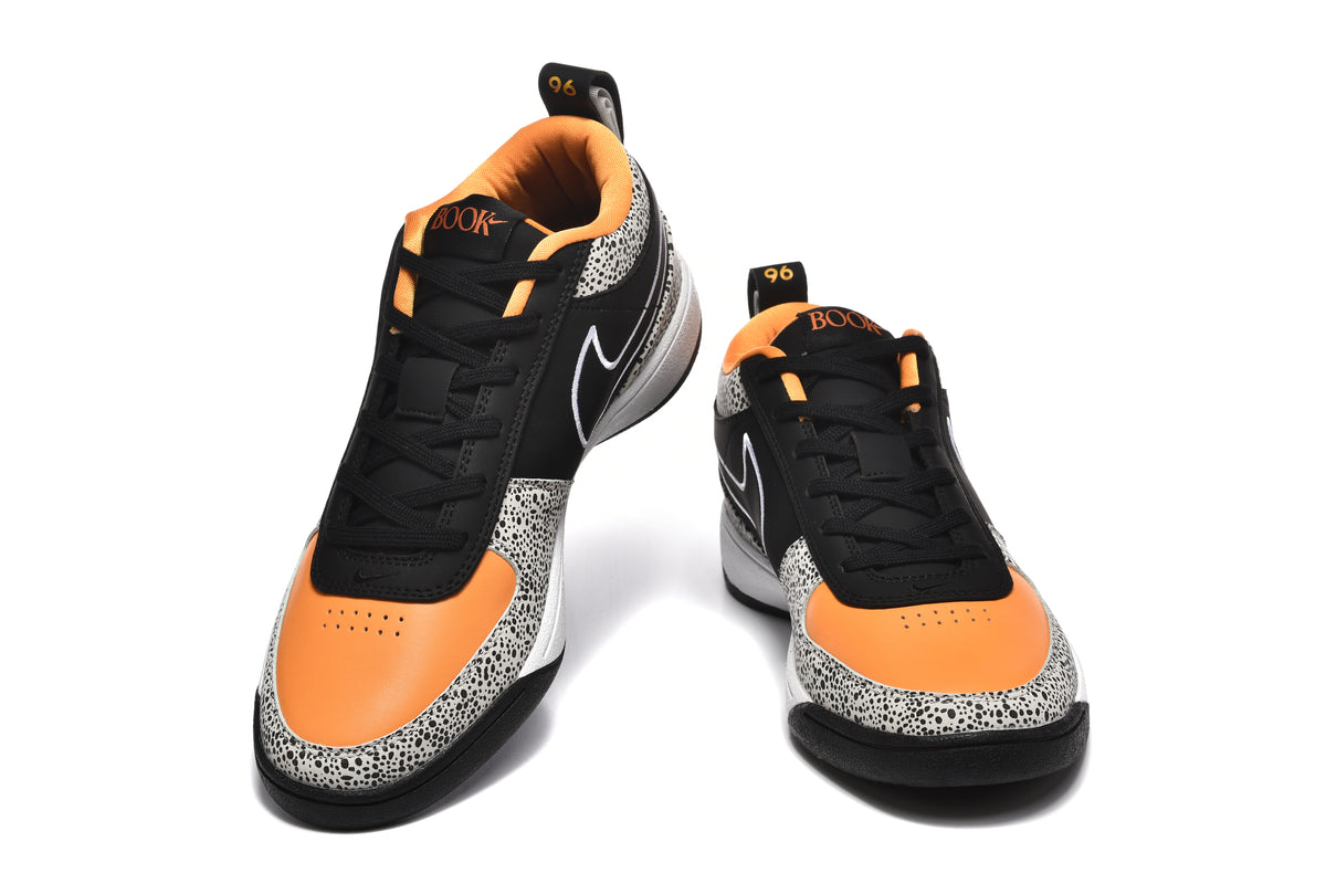 Pair of black, white, and orange Nike sneakers shown from the front, with spotted panels and orange toe sections.