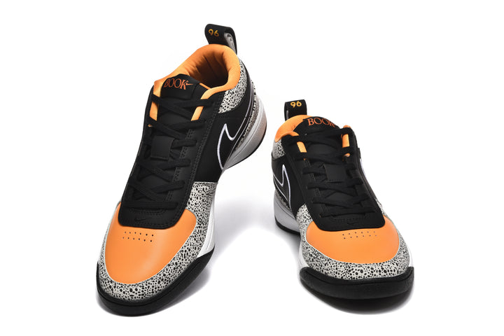 Pair of black, white, and orange Nike sneakers shown from the front, with spotted panels and orange toe sections.