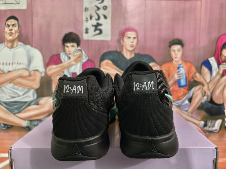 Rear view of black basketball sneakers showing padded heel panels, stitched detailing, and mint-green side accents.