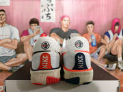 Rear view of white Nike basketball sneakers with contrasting orange-red and navy heel details and a speckled midsole.
