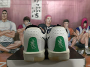 Rear view of white Nike basketball sneakers with green heel panels and visible heel branding, resting on a shoe box.