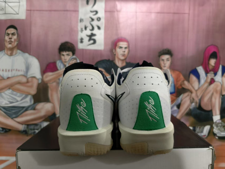 Rear view of white Nike basketball sneakers with green heel panels and visible heel branding, resting on a shoe box.