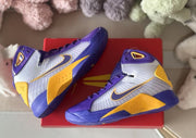 Pair of sneakers displayed on a red shoebox, showing the side panels and textured outsole edges.
