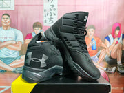 Angled view of black and gray Under Armour basketball sneakers showing the side branding, lace-up upper, and layered sole.