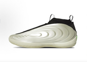 Side profile of a cream and black low-profile basketball shoe with concentric side detailing and a small green accent at the heel.