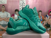 Angled view of paired green basketball-style sneakers showing the side profile, layered outsole, laces, and textured upper panels.