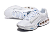 Angled view of white Nike Air Max DN sneakers with lace-up fastening and blue accents.