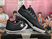 Angled view of a pair of black sneakers with white side graphics and textured outsoles.