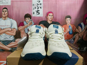 Front view of cream ASICS basketball sneakers with lace-up closures and navy toe accents.