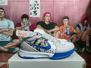 Side profile of a gray and white Nike basketball sneaker with a blue Swoosh, colorful dot pattern, and blue outsole.