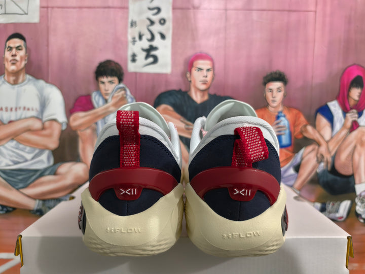 Rear view of white sneakers showing red heel pull tabs, dark navy heel panels, and cream-colored outsoles.
