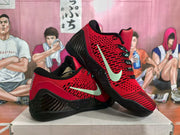 Angled view of red and black Nike basketball sneakers showing the Swoosh, patterned upper, black side structure, and textured outsole.