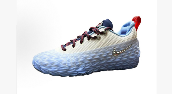 White low-top basketball sneaker with a sculpted textured sole, blue and red accents, patterned laces, and a metallic side emblem