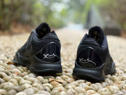 Rear view of both black sneakers showing padded collars and signature-style heel graphics.