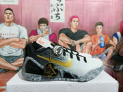 Side profile highlighting the white toe, black heel structure, gold side detail, decorative heart tag, and marbled outsole.