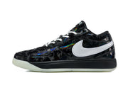 Profile view of a black low-top sneaker with white side branding, patterned panels, and a black midsole.