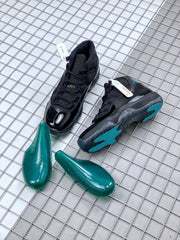 Pair of black sneakers displayed with blue outsole accents and two green shoe forms.