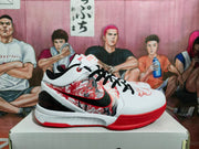White basketball sneaker with black laces, red patterned side panels, a black Nike Swoosh, and red outsole accents displayed on a shoe box.