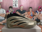 Side profile showing layered metallic gold panels, black inserts, and a textured rubber sole.