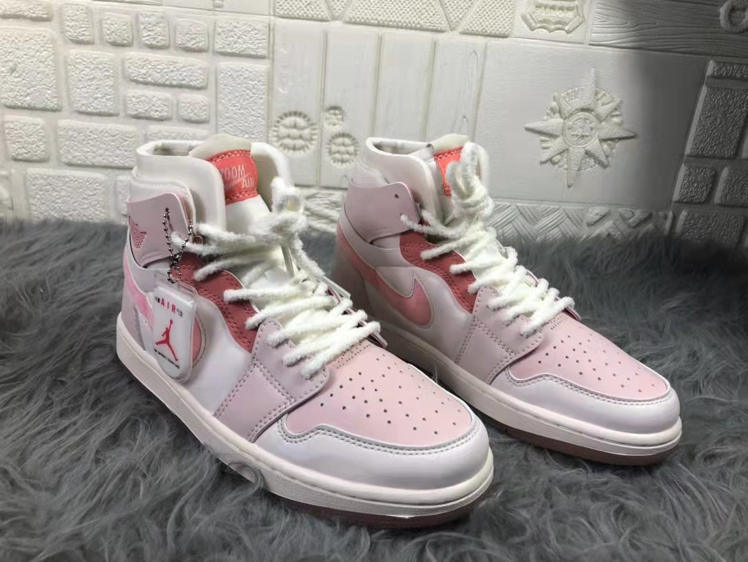 Pair of pink and white Air Jordan 1 sneakers shown from a front three-quarter angle.