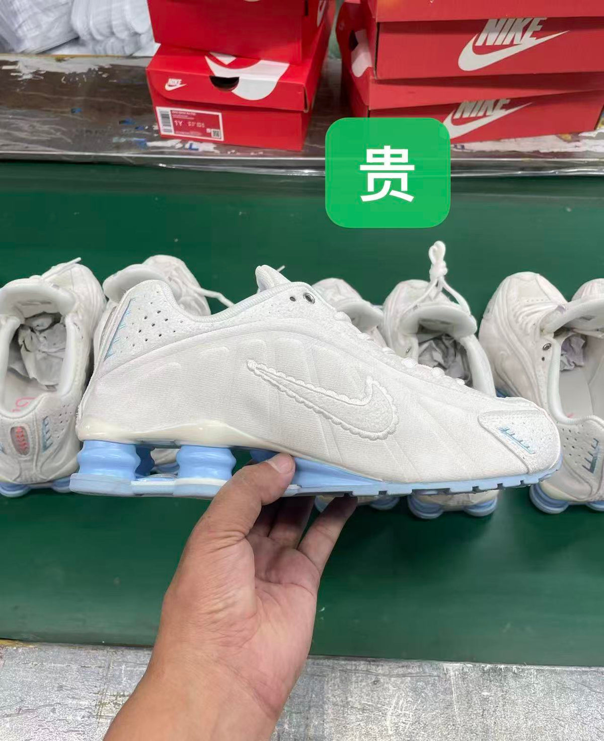 White Nike Shox-style sneaker with tonal Swoosh, perforated panels, and blue heel cushioning columns