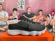 Side view of a black Nike sneaker showing the black Swoosh, textured upper, lacing system, and white sculpted sole.