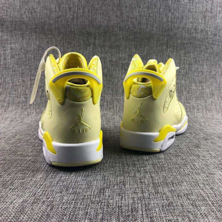 Rear view of the pale yellow high-top sneakers showing yellow collars, white midsoles, heel branding, and yellow outsole accents.