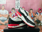 Pair of white, black, and red Jordan-branded sneakers shown from a three-quarter angle on a black box.
