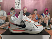 Side view showing perforated panels, black Swoosh branding, red detailing, and speckled midsole.