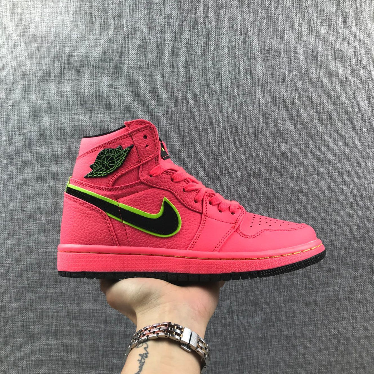 Side view of a hot pink Jordan 1 Mid sneaker with black and volt-green side branding.