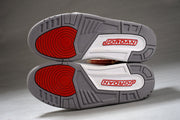 Close view of the gray outsoles with red circular traction sections and Jordan branding.